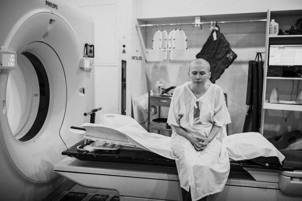 Rhiannon Abshoff sitting on MRI machine during her breast cancer treatment.